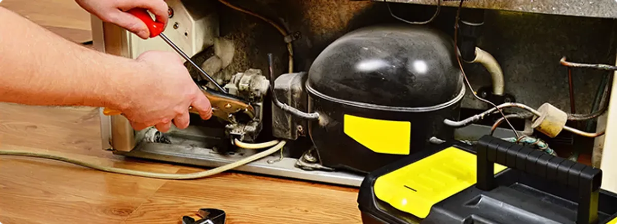 Refrigerator repair technician fixing the compressor and wiring in {city}, {state}